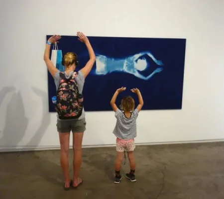 two gallery viewers backs and their arms are raised