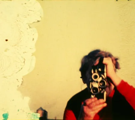 image of filmmaker dressed in red obscured by camera pointed directly at viewer