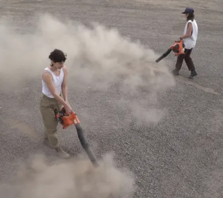 image of two people in the desert with leaf blowers