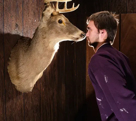 image of person nose-to-nose with taxidermied deer head on wall