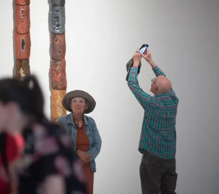 person taking photo of artwork on wall 
