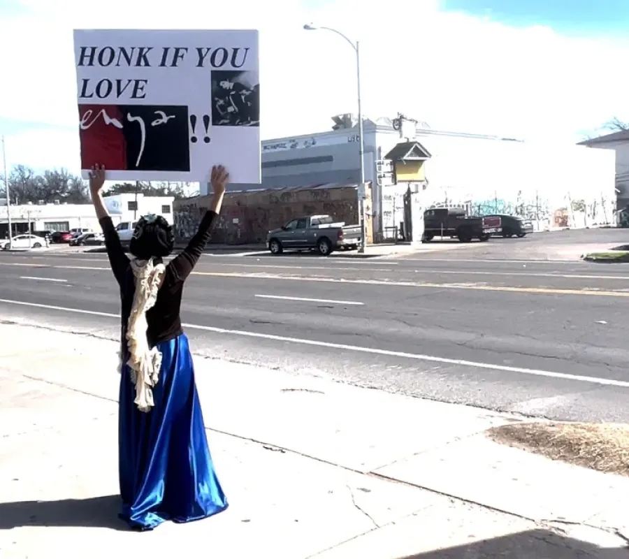 person holding sign on side of street