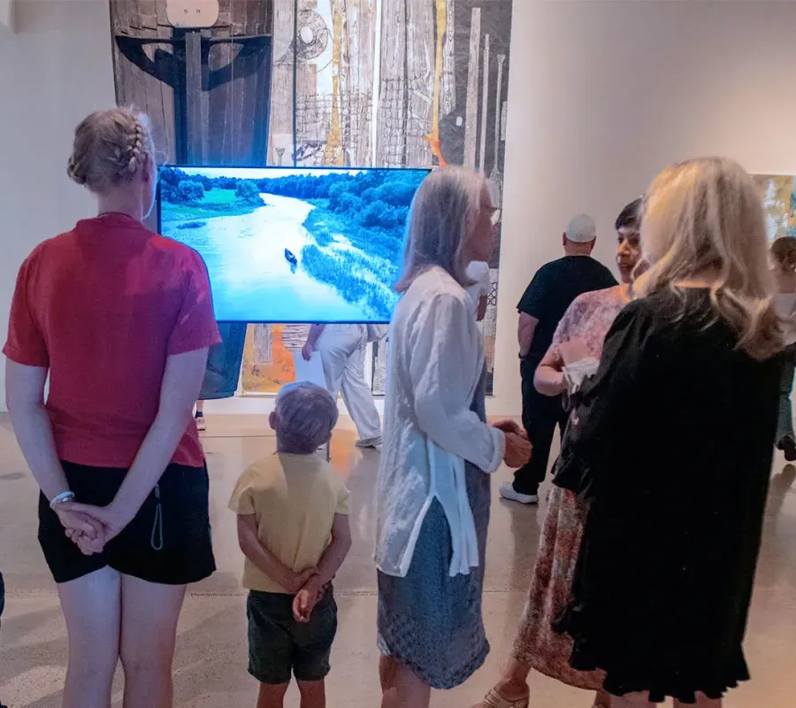 people looking at video on screen in gallery during opening reception