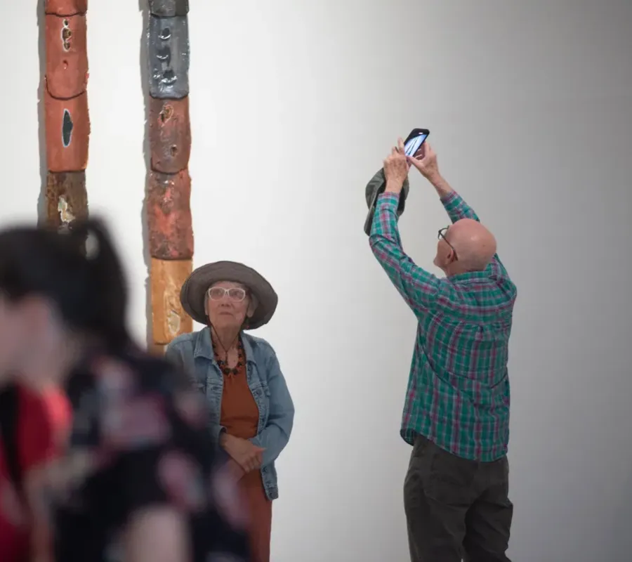 person taking photo of artwork on wall 