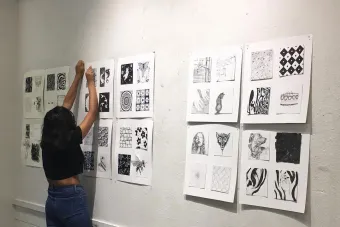 student pinning work onto the wall