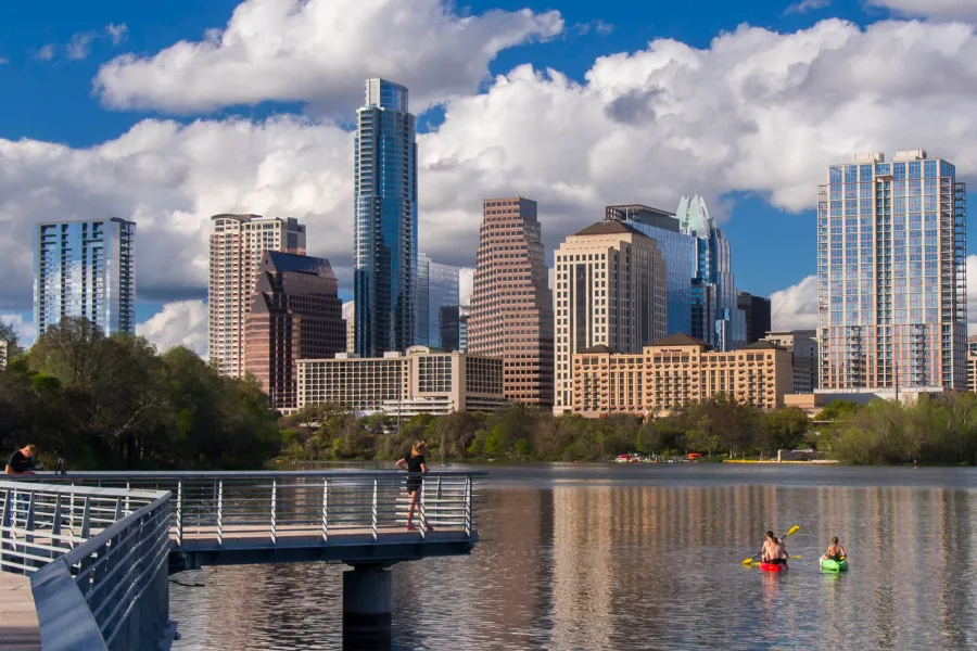 pedestrians on Town Lake boardwalk with Austin skyline in distance