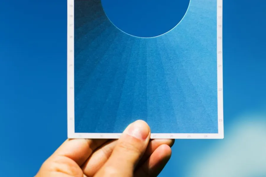 image of hand holding blue postcard against sky