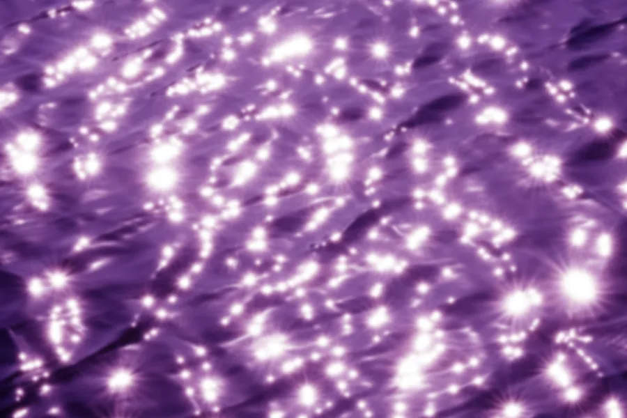 surface of water with ripples and cast in purple hue